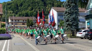 TVWU empfängt TV Würenlos
Von einem Eidgenössischen heimzukehren ist etwas ganz Besonderes. Dies galt auch für
den TV Würenlos, der von Lausanne per Bahn den Weg nach Hause fand.
Kaum war der Zug mit der Turnerfamilie des TV am Bahnhof Würenlos angekommen,
begannen die angetretenen Tambouren die Heimkehrer lautstark zu begrüssen. Die TVWU-ler
als einziger Verein, aber mit Schweizer und Vereinsfahne ausgerüstet sorgten bei den
Ankömmlingen für strahlende Gesichter. Nicht jeder wussten, dass sie so herzlich empfangen
würden. Umso mehr machte sich Begeisterung breit. Zur Freude aller grüssten sich die
Fahnen und gaben so diesem einmaligen Ereignis einen ehrenden und festlichen Auftakt.
Alsdann wurde zum Marsch durchs Dorf aufgestellt und gestartet. Die Tambouren führten den
stolzen und freudigen Zug bis auf den Schulhausplatz, wo viele Angehörige und Freunde der
Turnerfamilie warteten. Ein herzlicher Empfang mit kurzen Ansprachen und einem wunderbar
aufgebauten Apero rundete den Sonntagnachmittag ab.
Wir Tambouren freuen uns, dass wir die Turnerfamilie empfangen durften und wünschen allen
Mitgliedern weiterhin viel Freude an ihrem Hobby und gute Kameradschaft. #tvwürenlos #eidgenössischesturnfest #heicho #stolzufeuch @tvwuerenlos